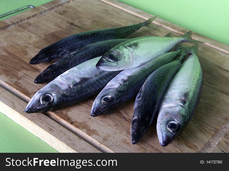 Close up of fresh mackerel fish on wooden table. Green background.