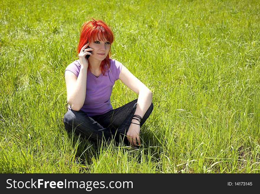 Redhead girl talking on the phone in a forest. Redhead girl talking on the phone in a forest