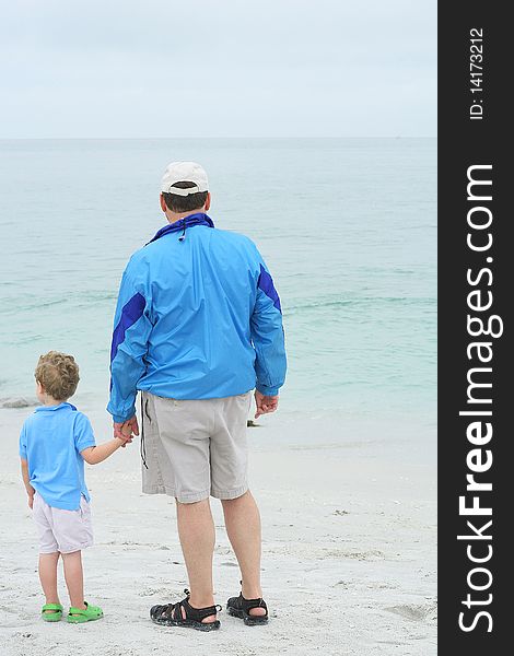 Shot of a father holding sons hand on the beach