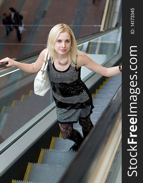 Beautiful young woman walking on escalator