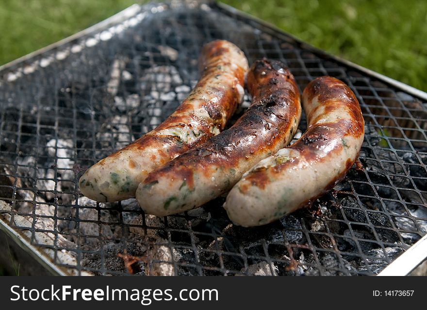 Nearly burnt sausages on simple outdoor picnic grill. Nearly burnt sausages on simple outdoor picnic grill