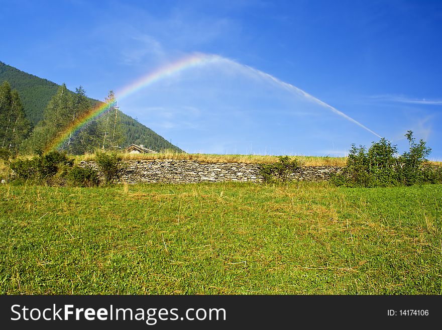 Watering A Garden In Mountain And Rainbow