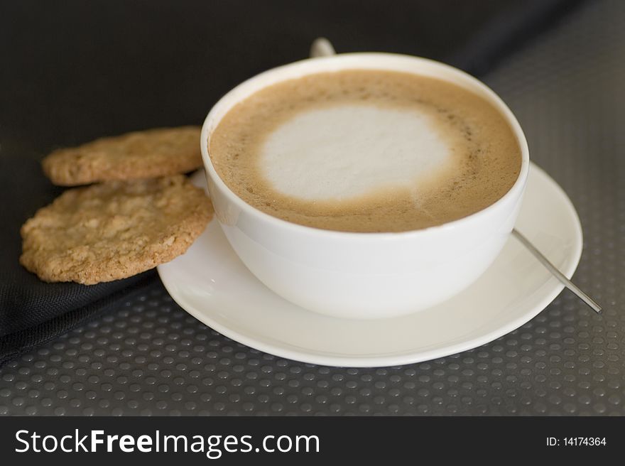 Close up shot of cappuccino cup with cookies and spoon. Close up shot of cappuccino cup with cookies and spoon