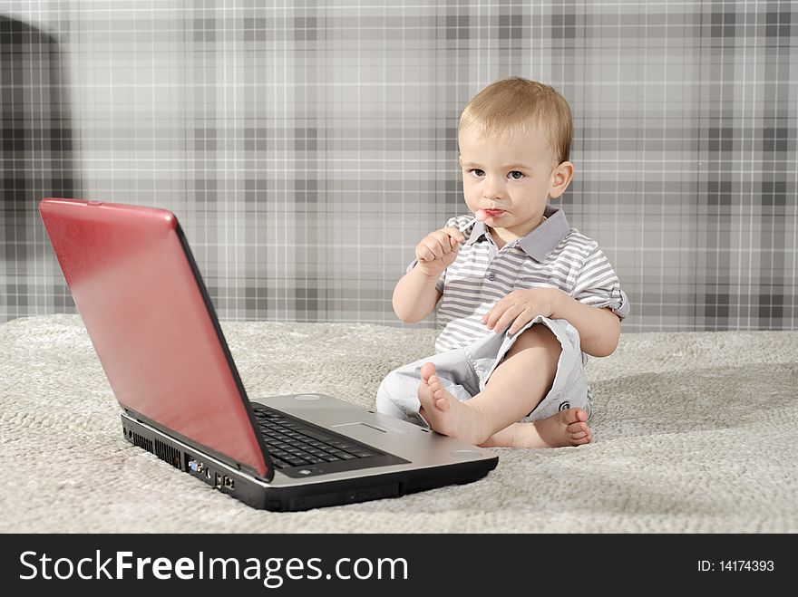 Boy playing with red notebook and eating lollipop. Boy playing with red notebook and eating lollipop