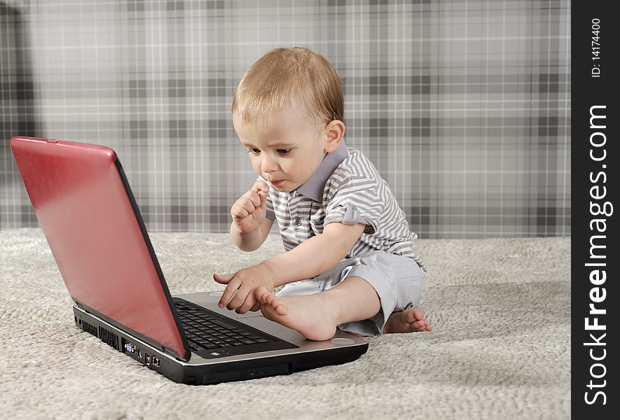 Boy playing with notebook and eating lollipop. Boy playing with notebook and eating lollipop