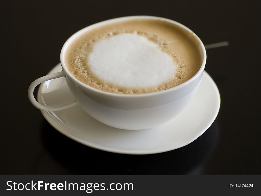 Cup of cappuccino coffee against black background. Cup of cappuccino coffee against black background