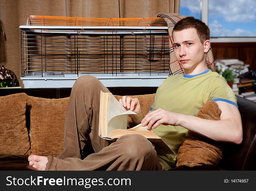 Handsome guy reading very thick book on his sofa. Handsome guy reading very thick book on his sofa