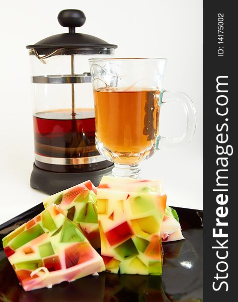 Fruit jelly with teapot and cup of tea on white background