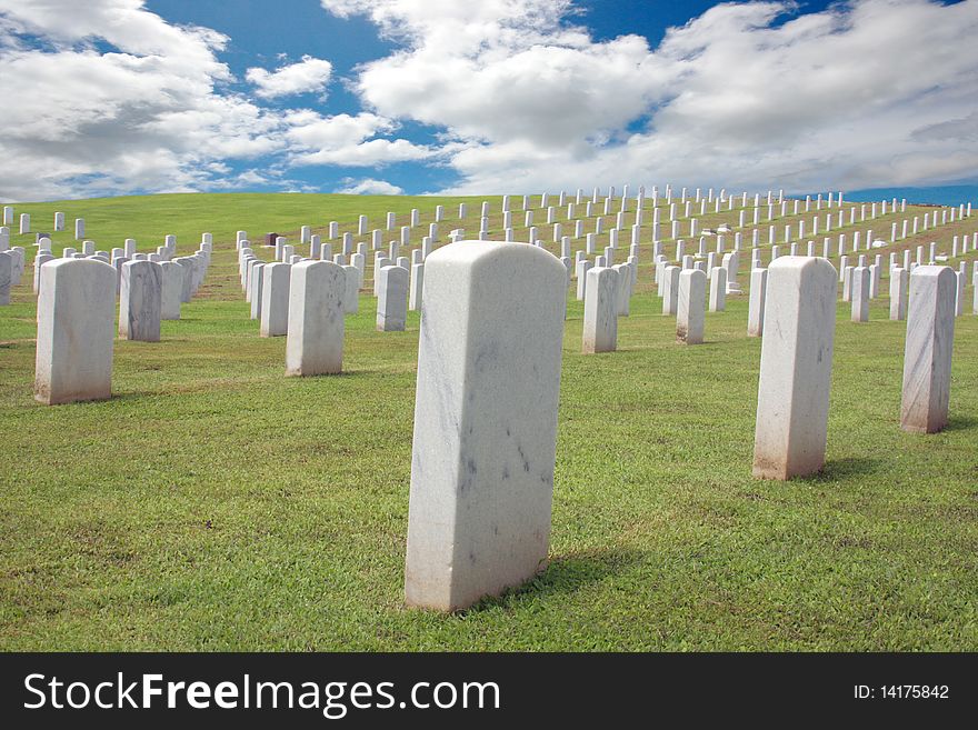 Cemetery on a hill top with blue sky and clouds in the background