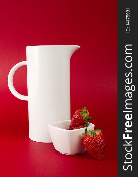 White jug with strawberry's on red background. White jug with strawberry's on red background