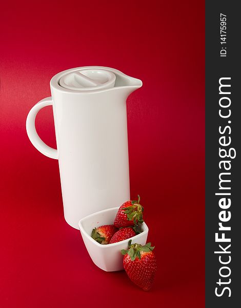 White jug with strawberry's on red background. White jug with strawberry's on red background