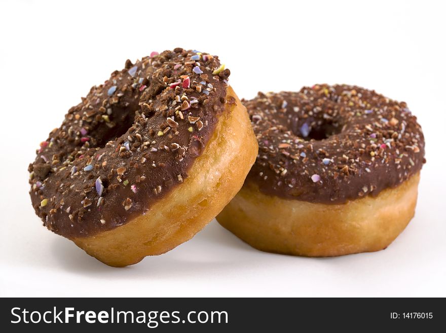 Two chocolate covered doughnuts over white. Two chocolate covered doughnuts over white