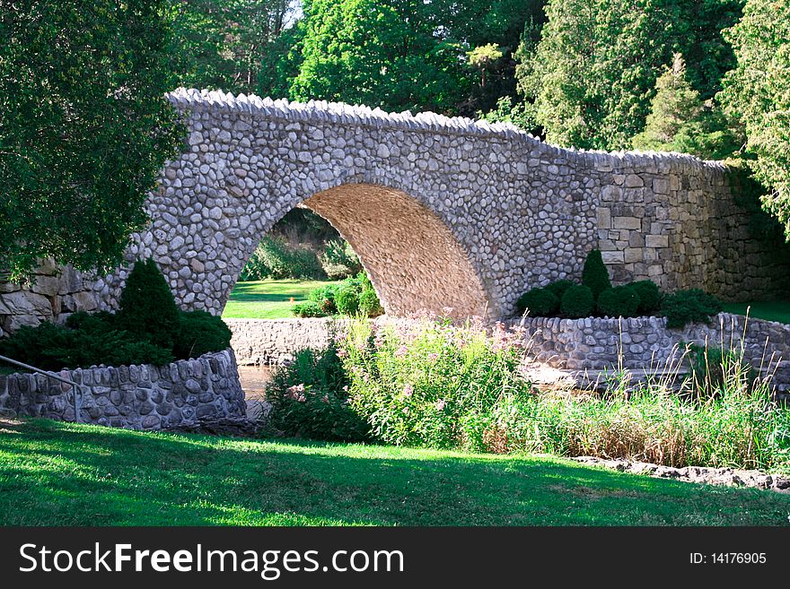 A stone bridge over a river in a fairy tale like park