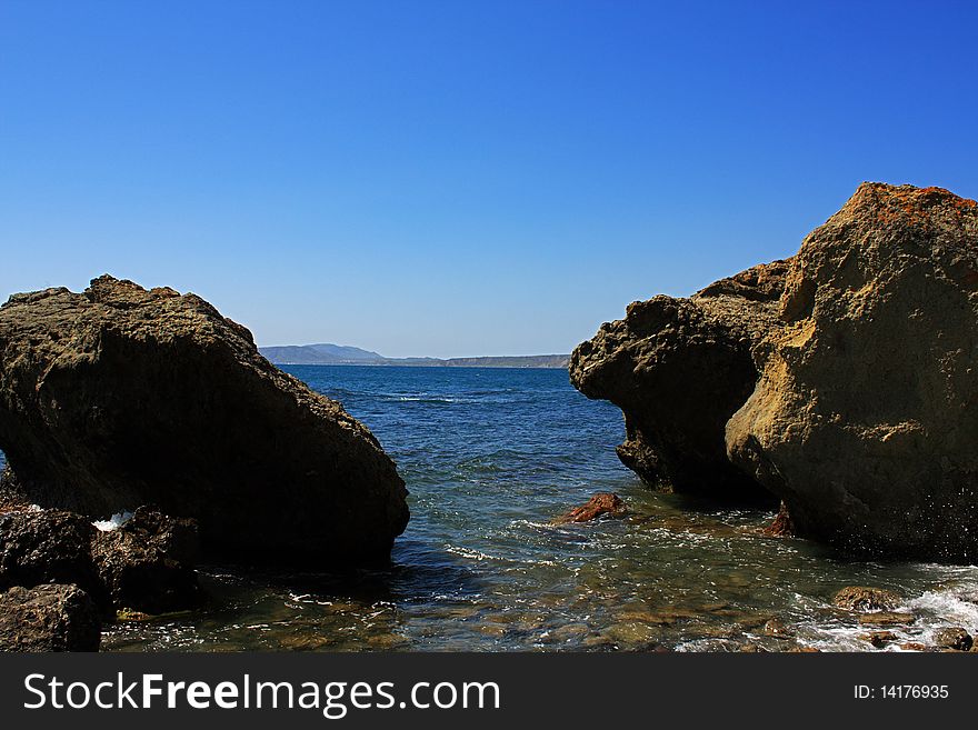 Seascape - a beautiful beach, sea and sky. In the foreground stones from the vent of an ancient volcano karadag. Seascape - a beautiful beach, sea and sky. In the foreground stones from the vent of an ancient volcano karadag