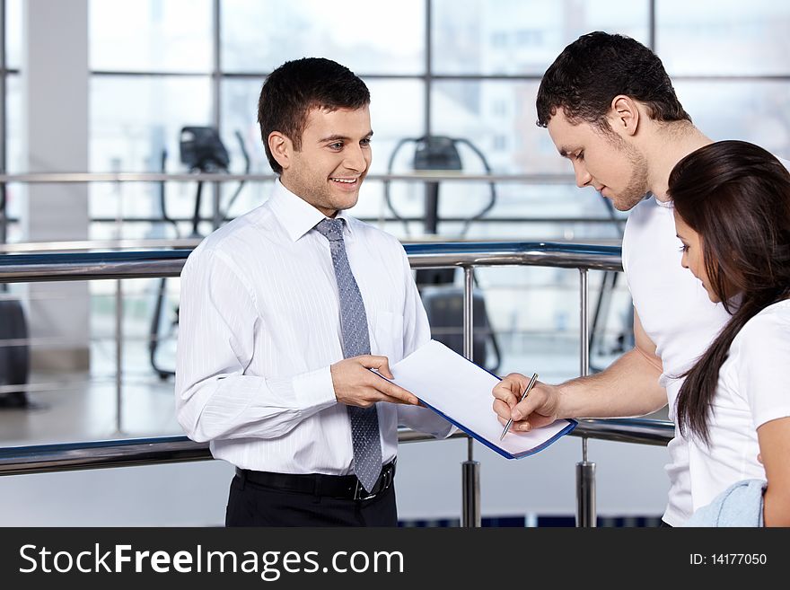 The young man signs the document in fitness club. The young man signs the document in fitness club