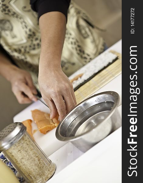 A sushi chef in action preparing a sushi dish with salmon