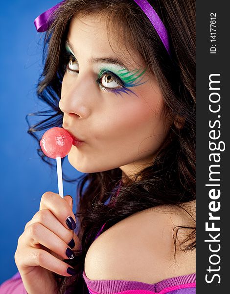 Beautiful girl colourful make-up licking lollipop looking up. Beautiful girl colourful make-up licking lollipop looking up