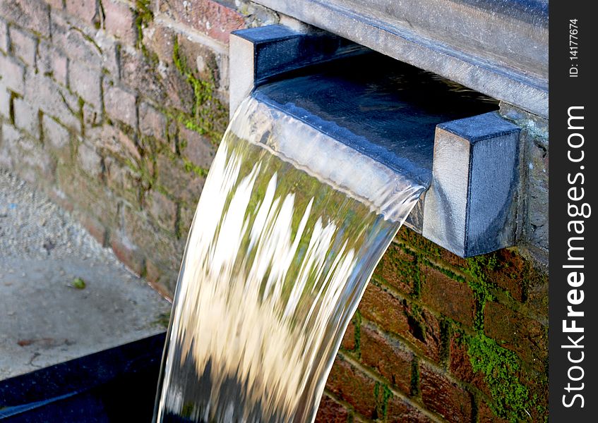 Small artificial waterfall or water cascade in a brick wall