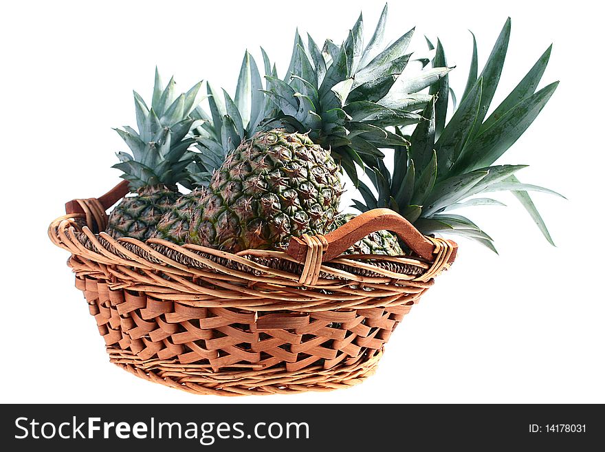 The crop of pineapples is collected in a wattled basket, a background white. The crop of pineapples is collected in a wattled basket, a background white.