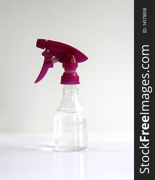 A clear spray bottle with a pink nozzle with a white background.