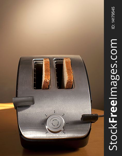 A toaster with two pieces of bread on a table. A toaster with two pieces of bread on a table.