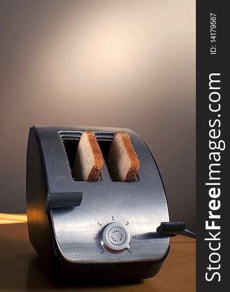 A toaster with two pieces of bread sits on a table. A toaster with two pieces of bread sits on a table.