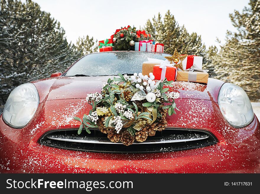 Car with Christmas wreath, tree and gifts in winter forest, closeup