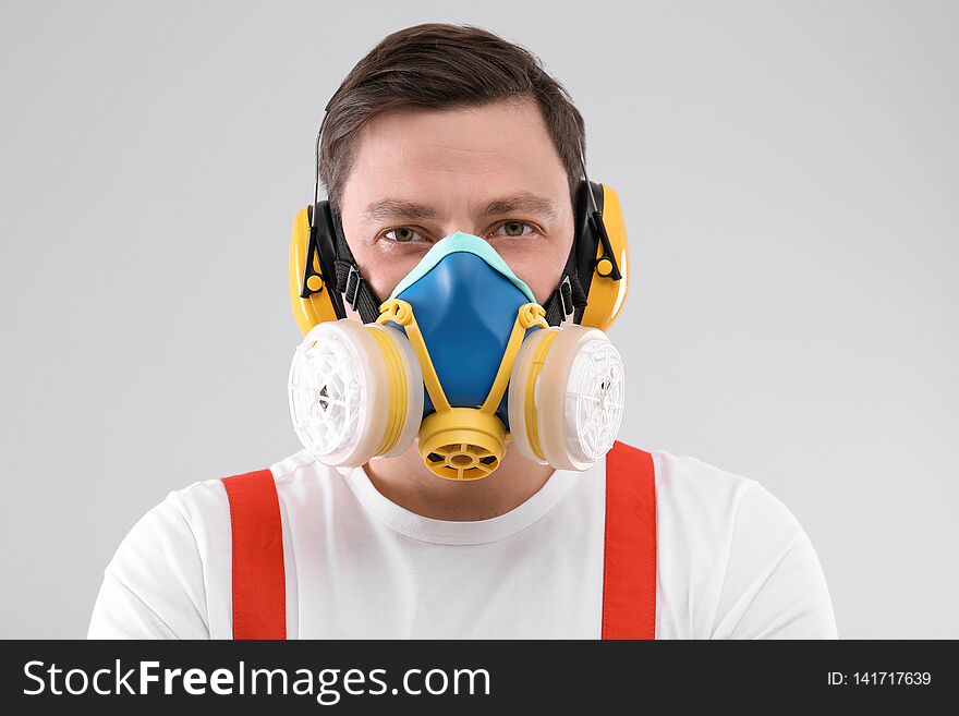 Male industrial worker in uniform on light background. Safety equipment
