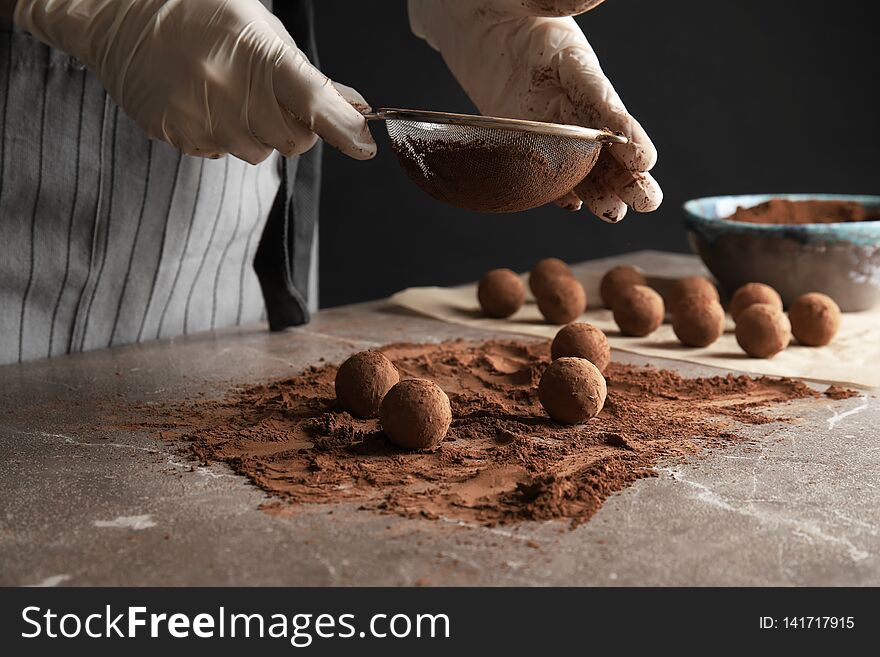 Woman preparing tasty chocolate truffles at table