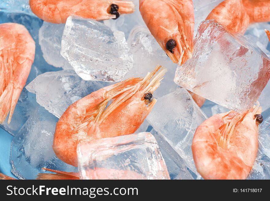 Raw shrimps and ice cubes as background, closeup
