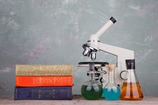 Books And Microscope On The Table On Grey Background Royalty Free Stock Image