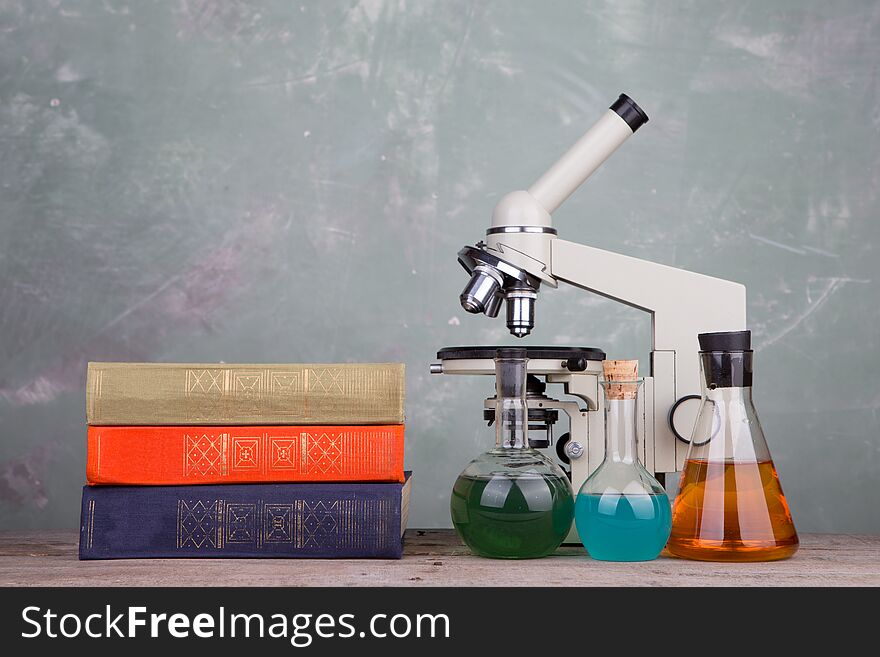 books and microscope on the table on grey background