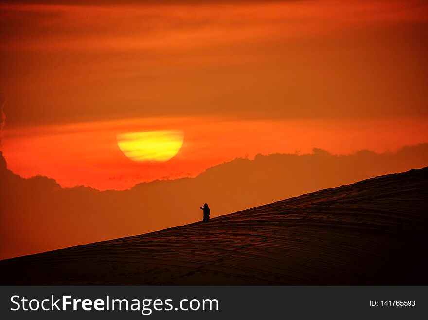 Woman sitting in the sand and watching the sun go down. Woman sitting in the sand and watching the sun go down