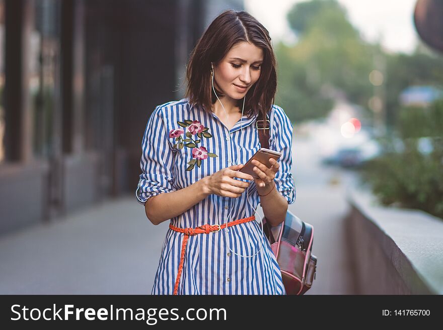 Brunette girl with phone and headphones in the street