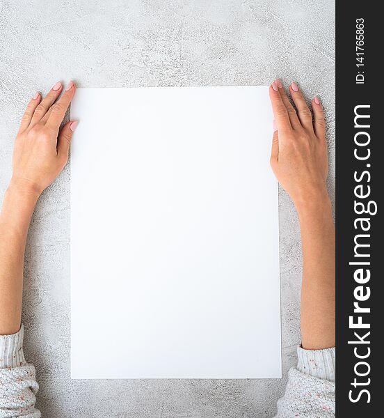 Girl`s hands holding a big white sheet of paper. Girl`s hands holding a big white sheet of paper