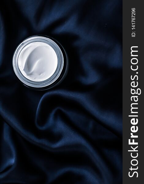 Beauty, anti-age cosmetics and skincare concept - Luxury face cream jar on a dark blue silk