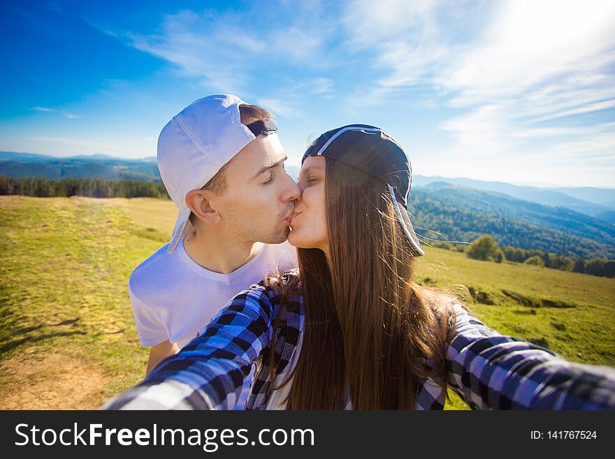 Young couple hiking taking selfie with smart phone. Happy young man and woman taking self portrait with mountain scenery backgrou