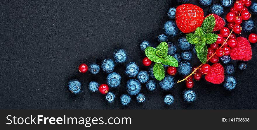 Berry mix on a black background with copy space. Strawberry, Raspberry, Red currant, Blueberry and Blackberry, top view