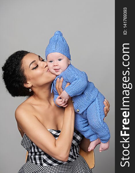 Pretty mixed race african american - caucasian women holding her caucasian baby in arms kissing. Pretty mixed race african american - caucasian women holding her caucasian baby in arms kissing