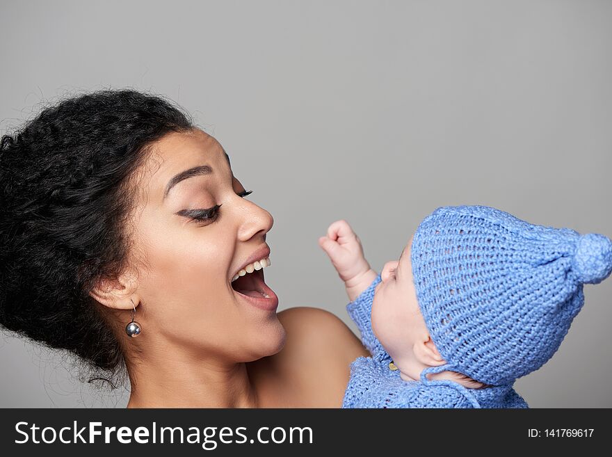 Closeup of happy mixed race african american - caucasian women holding her caucasian baby in arms smiling playful. Closeup of happy mixed race african american - caucasian women holding her caucasian baby in arms smiling playful