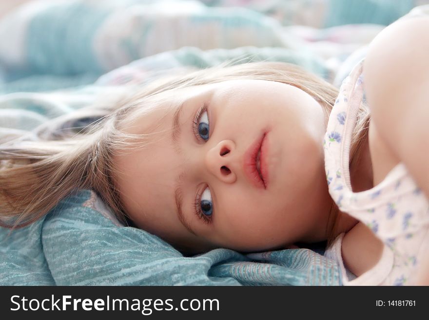 Beautiful little girl in the morning lying in bed