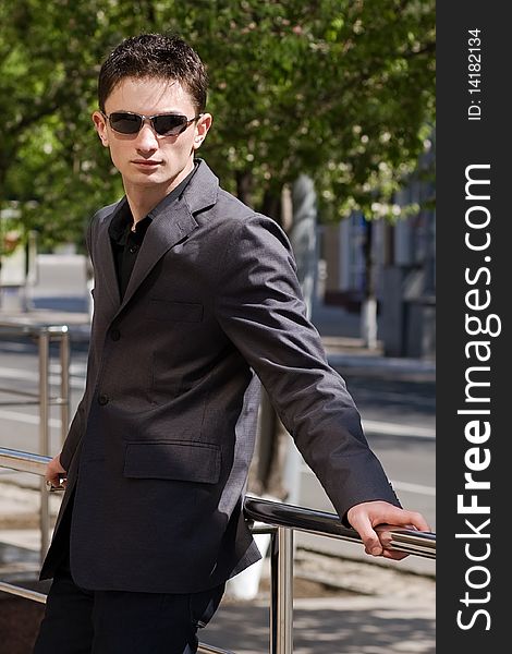 Businessman in sunglasses leans on handrails. Businessman in sunglasses leans on handrails