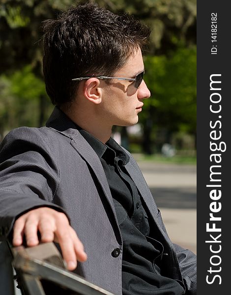 Young businessman sitting on a bench in the middle of a day. Young businessman sitting on a bench in the middle of a day