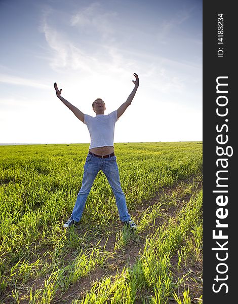 Man stay in green field with hands up