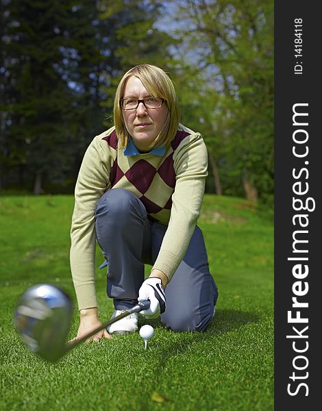 Woman golfer aiming for a swing with iron. Woman golfer aiming for a swing with iron.