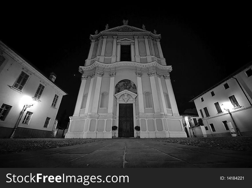 Church at night, the streets in Coccaglio (Italy). Church white and gray on black sky. Black and white.