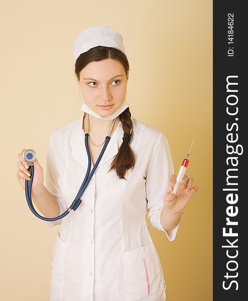 Portrait of young nurse or doctor with surgical face mask, syringe and stethoscope, studio background. Portrait of young nurse or doctor with surgical face mask, syringe and stethoscope, studio background.