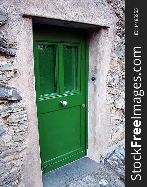 Detail of a green door in a restorated stone house in one italian country village