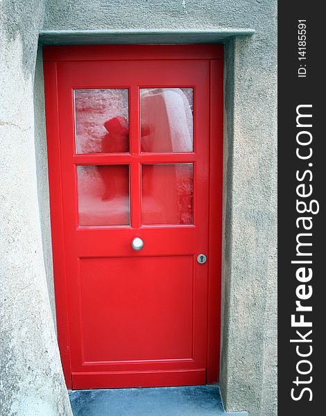 Detail of a red door in a restorated stone house in one italian country village