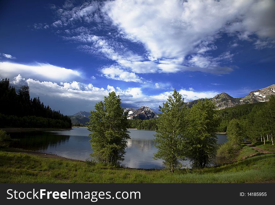 Mountain lake in the Spring with clouds with snow covered mountains reflected in the lake